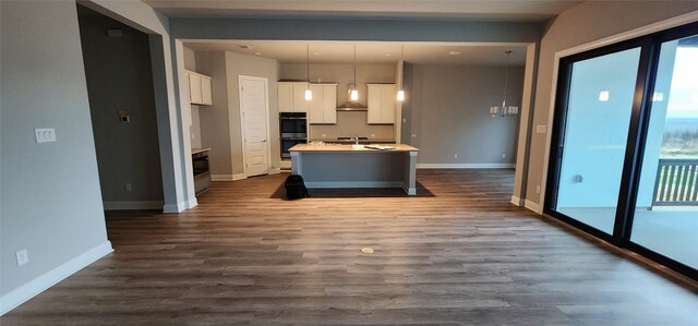 116 Merlin Ct, Cedar Creek, TX 78612 - kitchen with stainless steel double oven, white cabinetry, an island with sink, and dark wood-style floors
