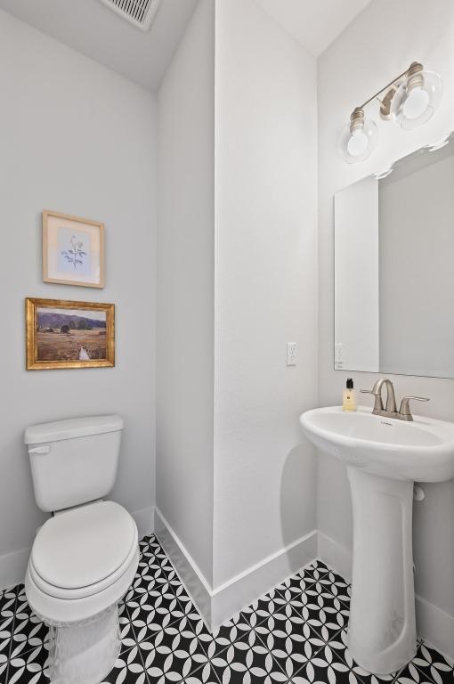 8513 Cottage Rose Dr, Austin, TX 78744 - half bathroom featuring baseboards, toilet, and a sink