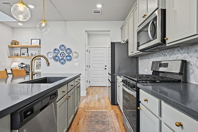 8513 Cottage Rose Dr, Austin, TX 78744 - kitchen with stainless steel appliances, a sink, light wood finished floors, dark countertops, and backsplash