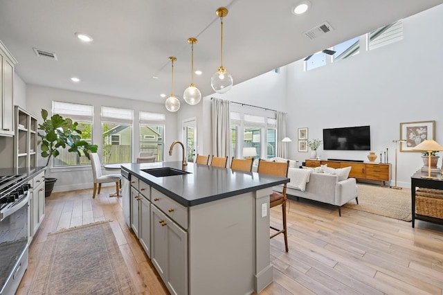 8513 Cottage Rose Dr, Austin, TX 78744 - kitchen with a sink, light wood-style floors, dark countertops, a breakfast bar area, and healthy amount of natural light