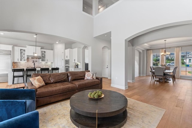 413 Mercer Falls Rd, Lakeway, TX 78738 - living room featuring arched walkways, a chandelier, light wood-type flooring, and baseboards