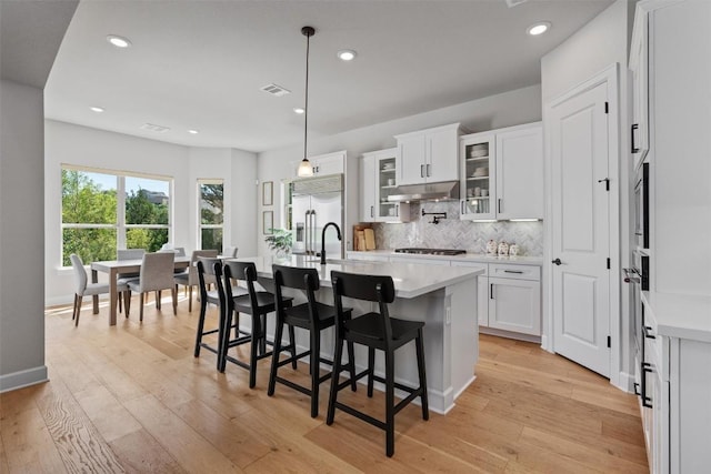 413 Mercer Falls Rd, Lakeway, TX 78738 - kitchen featuring stainless steel built in refrigerator, under cabinet range hood, light countertops, decorative backsplash, and a kitchen breakfast bar