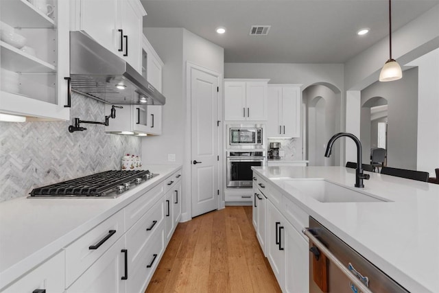 413 Mercer Falls Rd, Lakeway, TX 78738 - kitchen with appliances with stainless steel finishes, a sink, under cabinet range hood, white cabinets, and pendant lighting