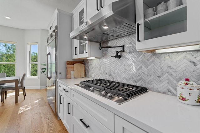 413 Mercer Falls Rd, Lakeway, TX 78738 - kitchen featuring exhaust hood, appliances with stainless steel finishes, light countertops, glass insert cabinets, and white cabinets