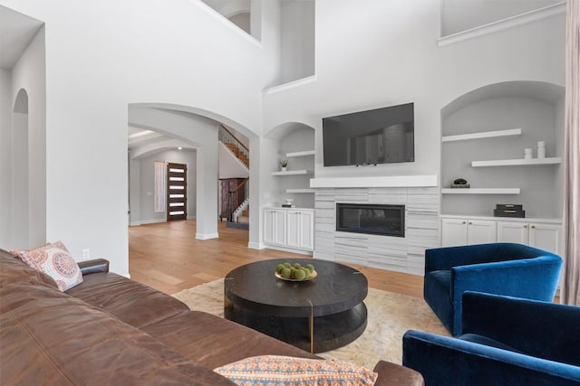 413 Mercer Falls Rd, Lakeway, TX 78738 - living area with built in shelves, wood finished floors, a glass covered fireplace, stairway, and baseboards