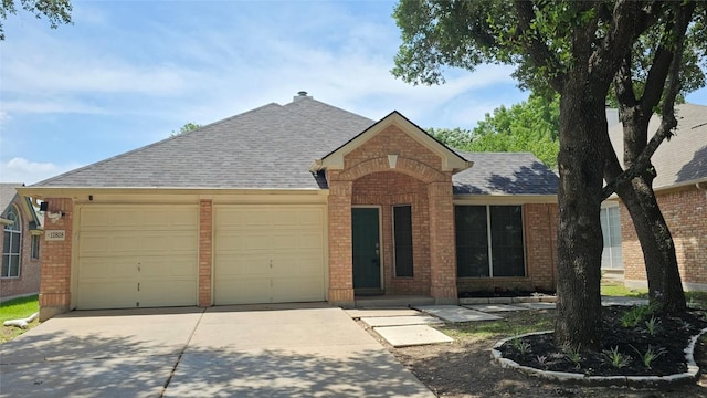 12828 Withers Way, Austin, TX 78727 - view of front facade featuring brick siding, roof with shingles, driveway, and a garage