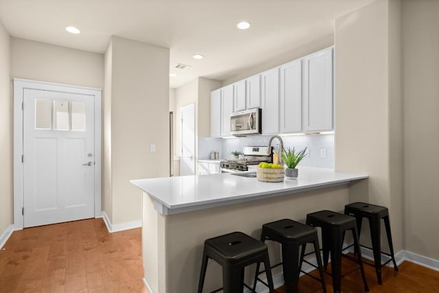8945 Parker Ranch Cir Unit B, Austin, TX 78748 - kitchen with appliances with stainless steel finishes, a breakfast bar area, light wood-style floors, and recessed lighting
