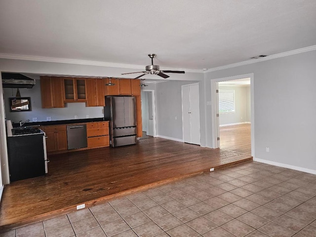 1407 Wilshire Blvd, Austin, TX 78722 - kitchen featuring stainless steel appliances, tile patterned floors, dark countertops, ornamental molding, and a ceiling fan