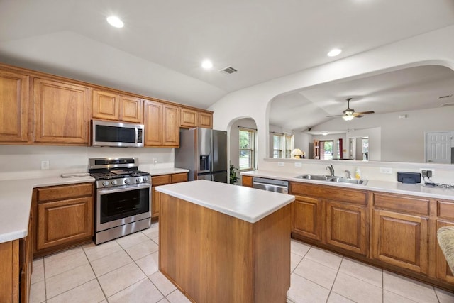 2801 Stirrup Cv, Leander, TX 78641 - kitchen featuring appliances with stainless steel finishes, lofted ceiling, arched walkways, a sink, and brown cabinets