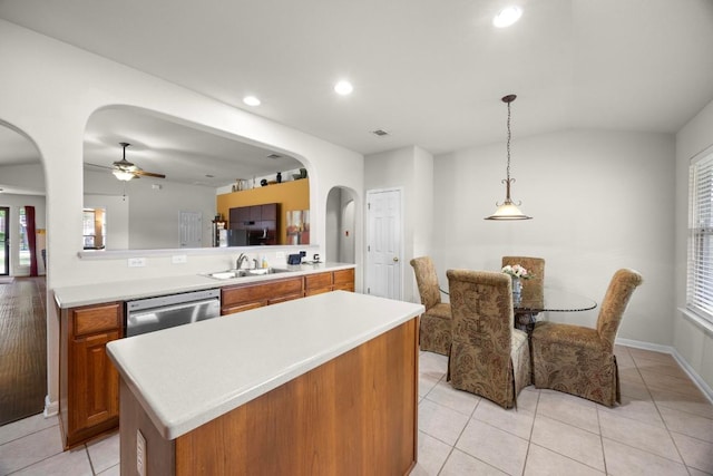 2801 Stirrup Cv, Leander, TX 78641 - kitchen featuring stainless steel dishwasher, brown cabinetry, a sink, arched walkways, and light countertops