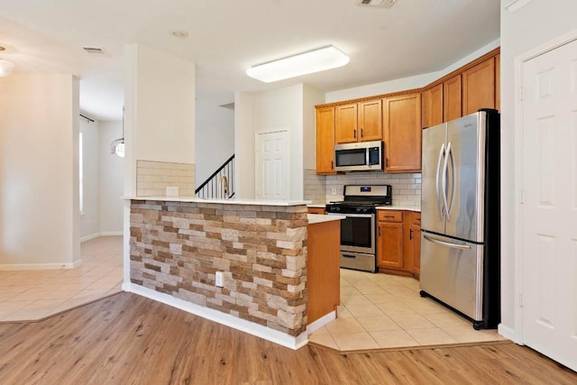 1900 Scofield Ridge Parkway Unit 1703, Austin, TX 78727 - kitchen featuring stainless steel appliances, light countertops, brown cabinetry, tasteful backsplash, and light tile patterned flooring