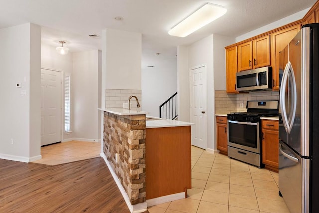 1900 Scofield Ridge Parkway Unit 1703, Austin, TX 78727 - kitchen featuring stainless steel appliances, a peninsula, a sink, decorative backsplash, and light countertops