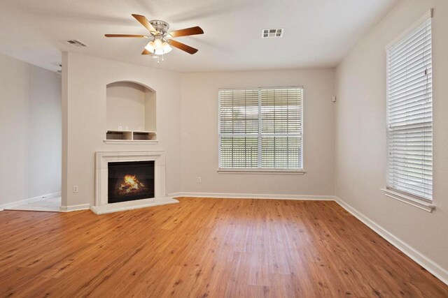 1900 Scofield Ridge Parkway Unit 1703, Austin, TX 78727 - unfurnished living room featuring wood finished floors, a ceiling fan, a warm lit fireplace, and baseboards