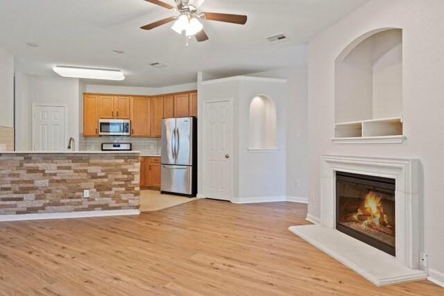 1900 Scofield Ridge Parkway Unit 1703, Austin, TX 78727 - kitchen featuring appliances with stainless steel finishes, light wood-style floors, a ceiling fan, backsplash, and light countertops