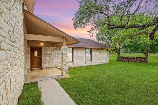 708 Post Oak Dr, Dripping Springs, TX 78620 - view of exterior entry with stone siding, a yard, and roof with shingles