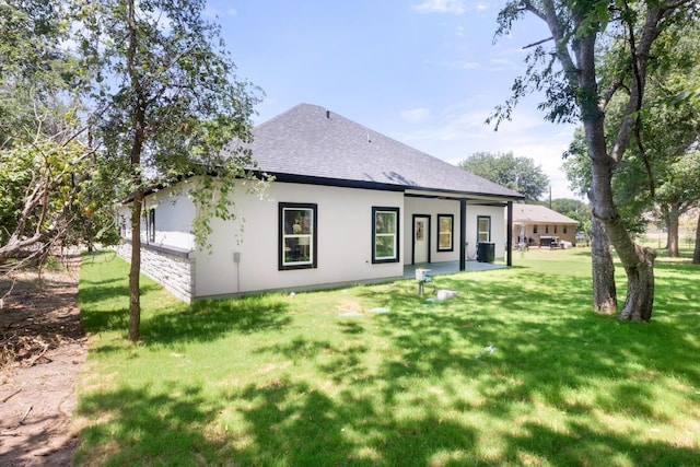 147 Puu Waa Waa Ln, Bastrop, TX 78602 - rear view of house with roof with shingles, a yard, and stucco siding