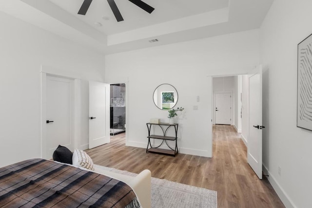147 Puu Waa Waa Ln, Bastrop, TX 78602 - bedroom featuring a tray ceiling, light wood finished floors, and a ceiling fan
