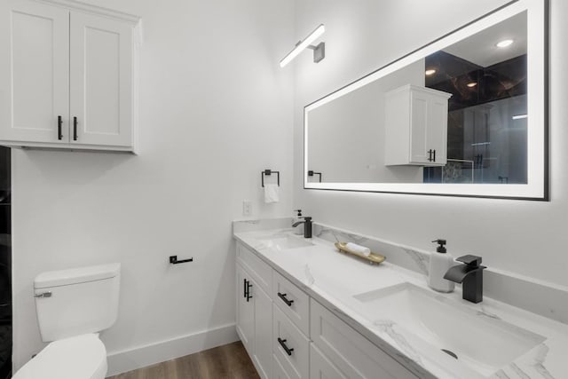 147 Puu Waa Waa Ln, Bastrop, TX 78602 - bathroom with double vanity, toilet, baseboards, wood finished floors, and a shower
