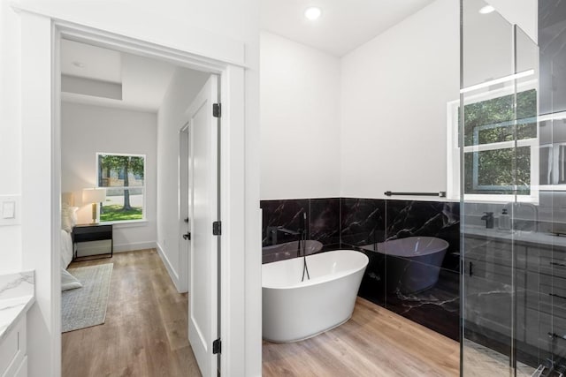 147 Puu Waa Waa Ln, Bastrop, TX 78602 - bathroom featuring a freestanding bath, vanity, wood finished floors, wainscoting, and tile walls