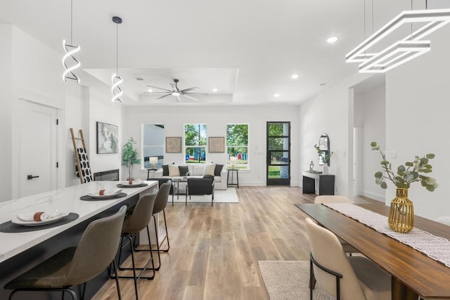 147 Puu Waa Waa Ln, Bastrop, TX 78602 - dining room featuring light wood-style floors, a tray ceiling, recessed lighting, a ceiling fan, and baseboards