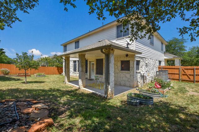 14800 Banbridge Trl, Austin, TX 78717 - rear view of house with a patio area, stone siding, and a vegetable garden