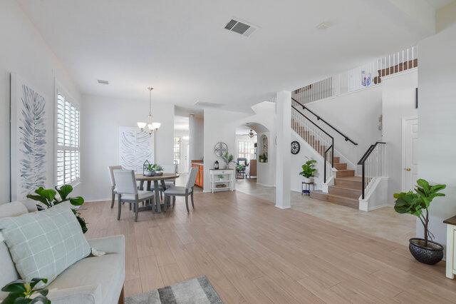 14800 Banbridge Trl, Austin, TX 78717 - living area with arched walkways, stairs, light wood-type flooring, a chandelier, and baseboards