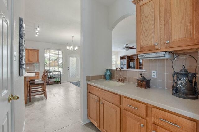 14800 Banbridge Trl, Austin, TX 78717 - kitchen featuring arched walkways, tasteful backsplash, light countertops, a chandelier, and light tile patterned floors