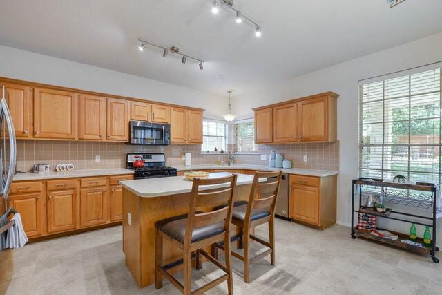 14800 Banbridge Trl, Austin, TX 78717 - kitchen featuring stainless steel appliances, light countertops, a center island, decorative backsplash, and a kitchen breakfast bar