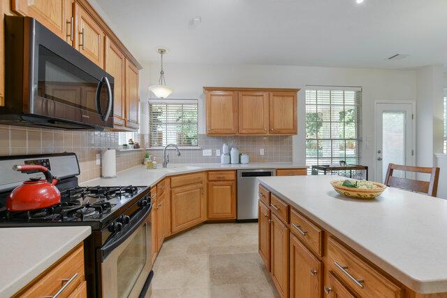 14800 Banbridge Trl, Austin, TX 78717 - kitchen with appliances with stainless steel finishes, tasteful backsplash, light countertops, hanging light fixtures, and a kitchen island