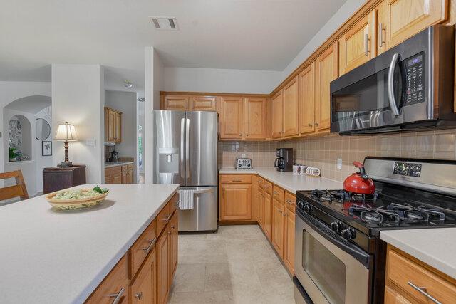 14800 Banbridge Trl, Austin, TX 78717 - kitchen featuring appliances with stainless steel finishes, light countertops, arched walkways, and tasteful backsplash