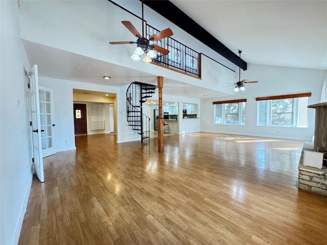 11804 Buckingham Rd, Austin, TX 78759 - unfurnished living room with ceiling fan, stairs, baseboards, wood finished floors, and high vaulted ceiling