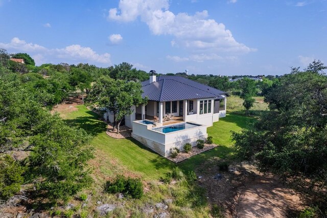 104 Megan Ln, Horseshoe Bay, TX 78657 - back of property with metal roof, a yard, a chimney, and an outdoor pool