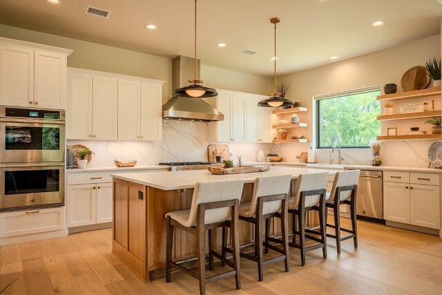 104 Megan Ln, Horseshoe Bay, TX 78657 - kitchen featuring appliances with stainless steel finishes, open shelves, a center island, light countertops, and white cabinetry
