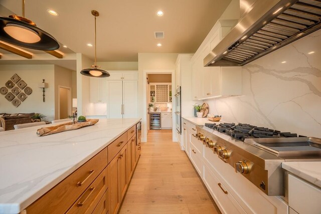 104 Megan Ln, Horseshoe Bay, TX 78657 - kitchen featuring wall chimney exhaust hood, appliances with stainless steel finishes, light wood finished floors, white cabinetry, and recessed lighting