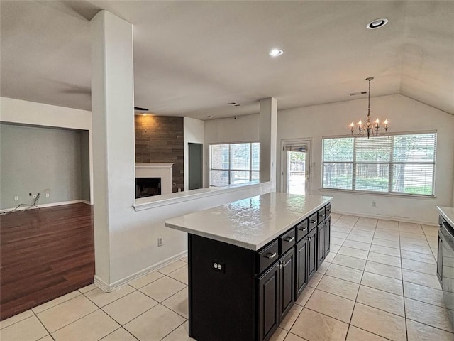 11708 Pillion Pl, Manor, TX 78653 - kitchen featuring dark cabinets, a fireplace, light countertops, open floor plan, and a chandelier