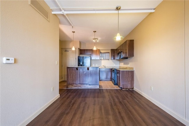711 W 26th St Unit 703, Austin, TX 78705 - kitchen with black appliances, dark wood-style floors, a breakfast bar area, baseboards, and light countertops