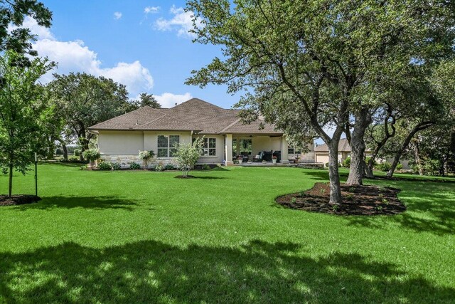 313 Aldea Cv, Georgetown, TX 78633 - rear view of house featuring stone siding, stucco siding, a lawn, and roof with shingles