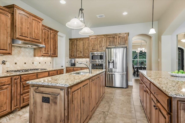 313 Aldea Cv, Georgetown, TX 78633 - kitchen with appliances with stainless steel finishes, an island with sink, arched walkways, under cabinet range hood, and backsplash