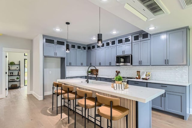 4803 Philco Dr, Austin, TX 78745 - kitchen with stainless steel microwave, a sink, backsplash, light wood-type flooring, and glass insert cabinets