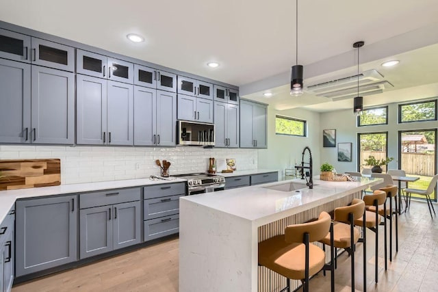 4803 Philco Dr, Austin, TX 78745 - kitchen featuring appliances with stainless steel finishes, a sink, backsplash, a kitchen bar, and recessed lighting