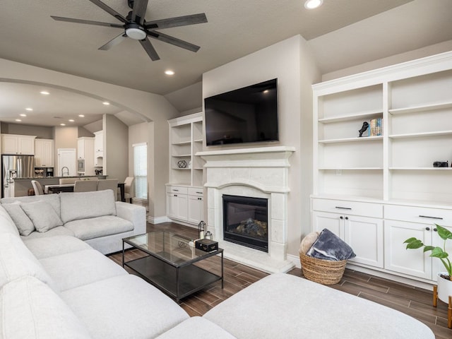 500 Cortona Ln, Georgetown, TX 78628 - living room featuring dark wood finished floors, a ceiling fan, a glass covered fireplace, arched walkways, and recessed lighting