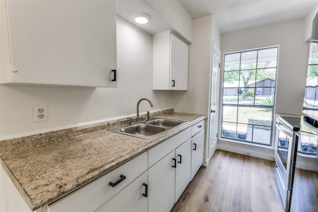 4709 Brassiewood Dr, Austin, TX 78744 - kitchen featuring a sink, light wood-style flooring, and white cabinets
