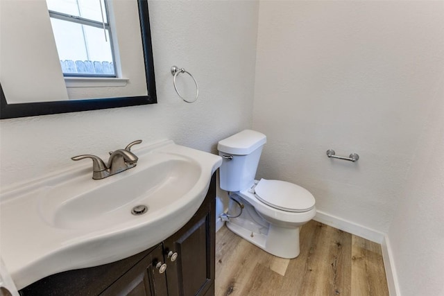 4709 Brassiewood Dr, Austin, TX 78744 - bathroom featuring wood finished floors, vanity, toilet, baseboards, and a textured wall