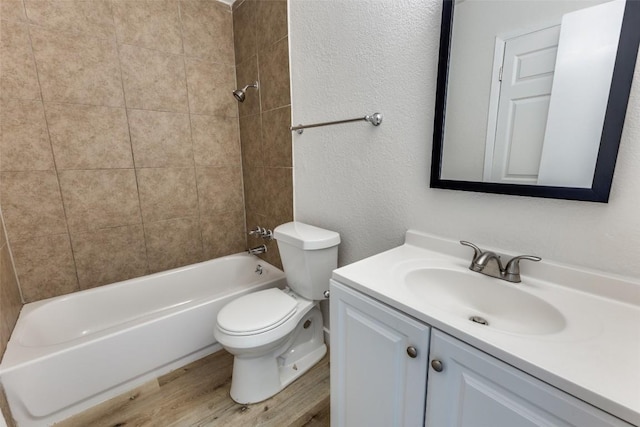 4709 Brassiewood Dr, Austin, TX 78744 - full bathroom featuring toilet, vanity, wood finished floors, a textured wall, and bathtub / shower combination