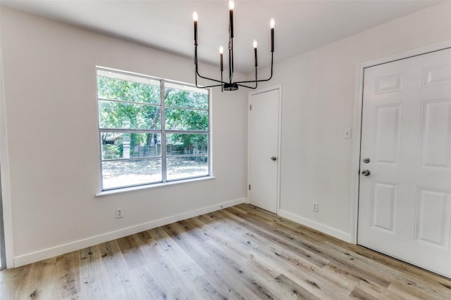 4709 Brassiewood Dr, Austin, TX 78744 - unfurnished dining area with a chandelier, light wood-style floors, and baseboards