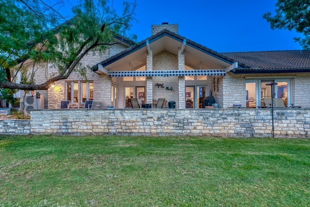 2704 Aurora, Horseshoe Bay, TX 78657 - rear view of property with a chimney, stone siding, and a yard