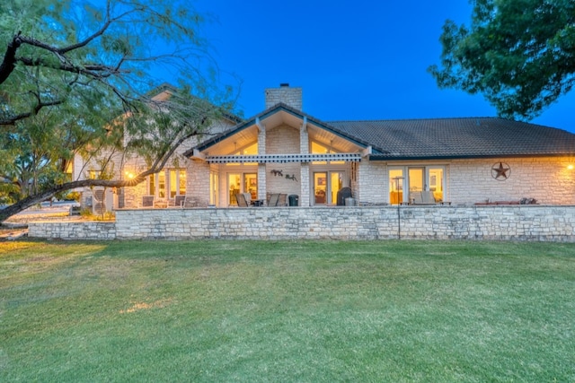 2704 Aurora, Horseshoe Bay, TX 78657 - back of property featuring a chimney, a lawn, and stone siding