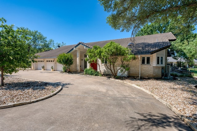2704 Aurora, Horseshoe Bay, TX 78657 - ranch-style home with a tiled roof, a garage, concrete driveway, and stone siding