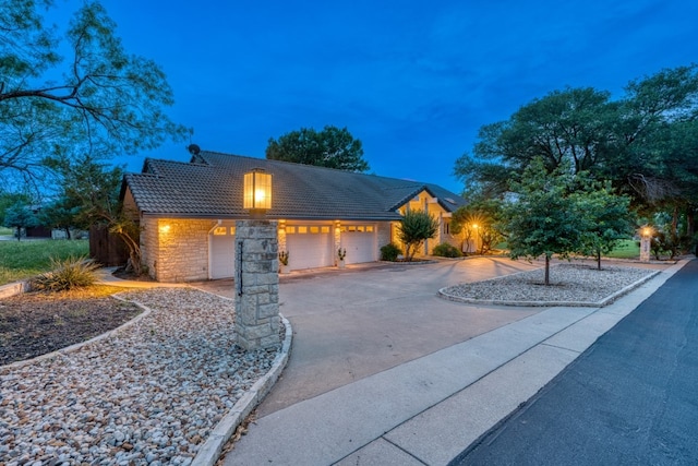 2704 Aurora, Horseshoe Bay, TX 78657 - view of front of home featuring a tile roof, an attached garage, stone siding, and concrete driveway