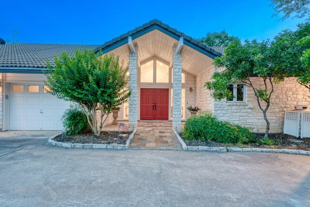 2704 Aurora, Horseshoe Bay, TX 78657 - doorway to property with an attached garage, stone siding, concrete driveway, and a tile roof